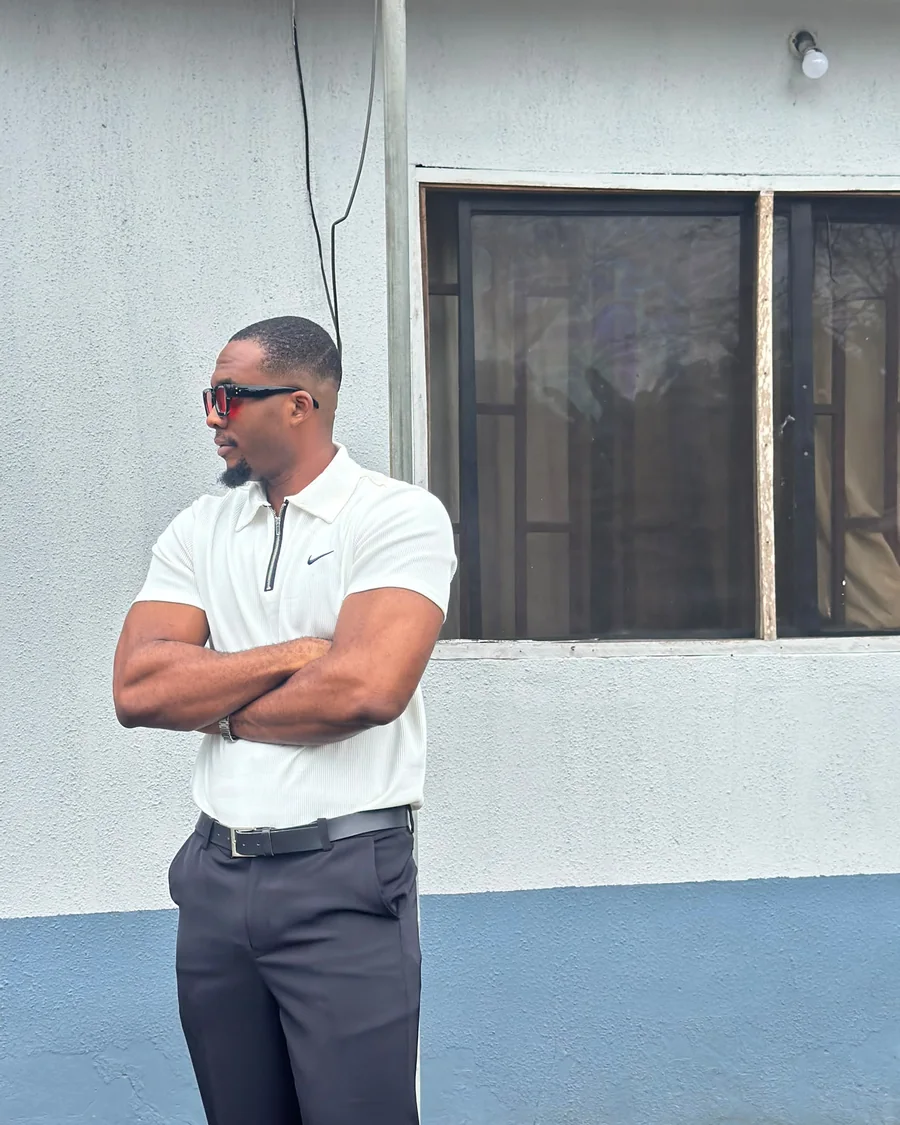 Emmanuel in a white polo with his arms crossed