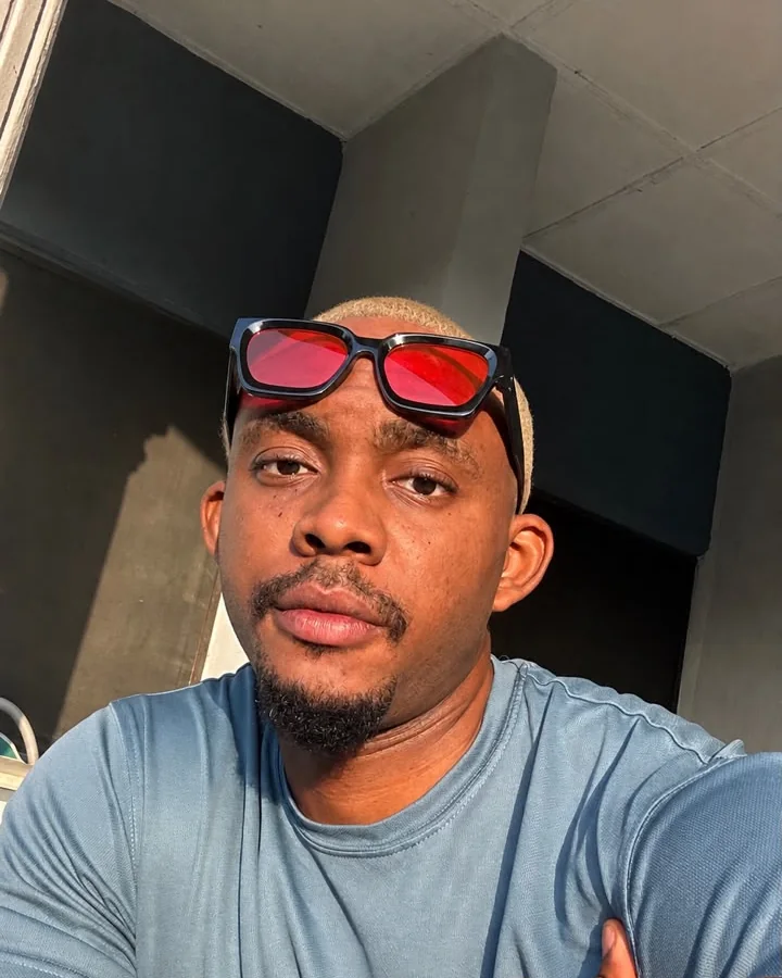 Selfie of Emmanuel with red-lensed glasses on his head